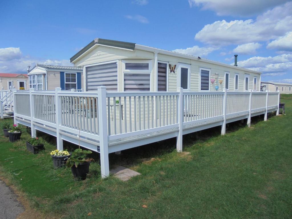 a white mobile home with a white fence at Waterside: Waterside Salisbury:- 6 Berth Large Wrap Around Veranda in Ingoldmells