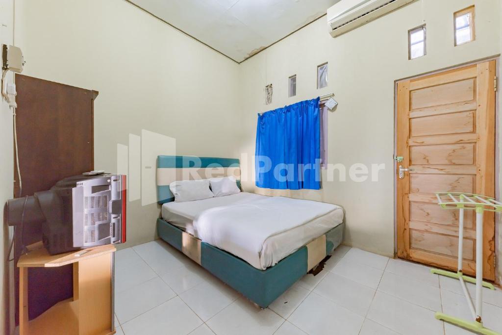 a bedroom with a bed and a tv in it at Ana Guest House Syariah Mitra RedDoorz in Banjarbaru