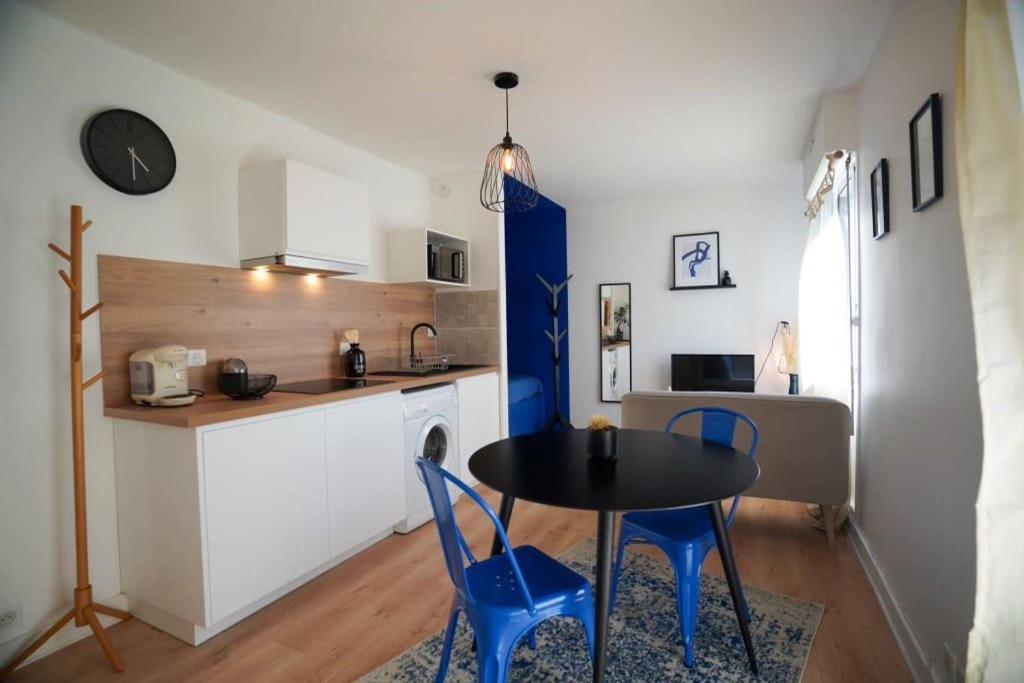 a kitchen with a table and blue chairs in a room at Studio Majorelle in Quimper
