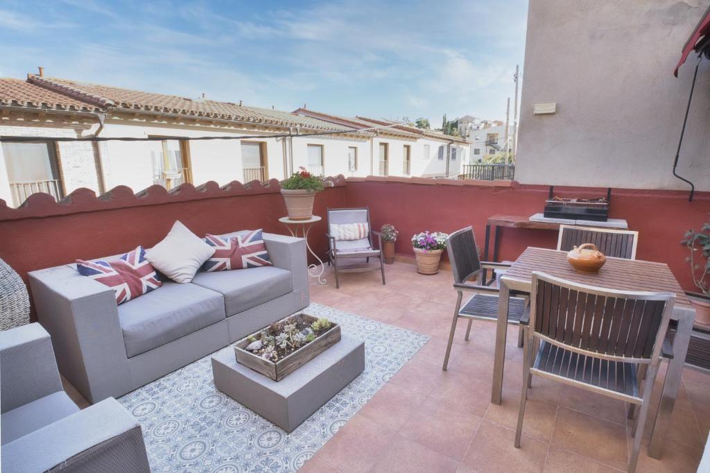 une terrasse avec un canapé, une table et des chaises dans l'établissement LES LLÚDRIGUES. Casa Loft con encantadora terraza, à Arnés