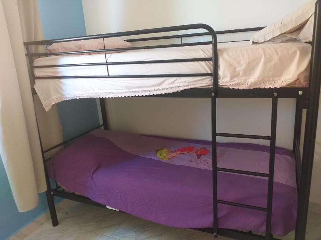 a bunk bed in a room with a purple sheet at شاليه ارضي بجنينه علي البسين مباشرة in Dawwār al Ḩajj Aḩmad