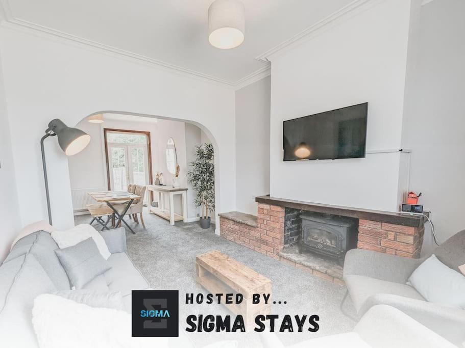 a living room with a white couch and a fireplace at Valley Park House - By Sigma Stays in Crewe