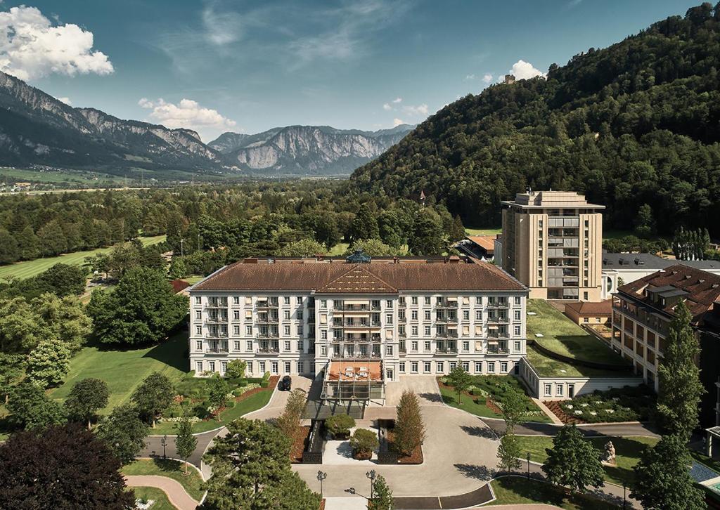 an aerial view of a building with mountains in the background at Grand Resort Bad Ragaz in Bad Ragaz