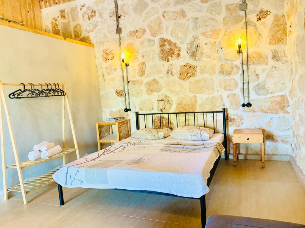 a bedroom with a bed and a stone wall at Bademlique Stone Rooms in Kaş