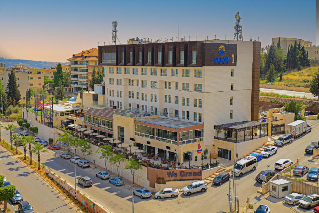 a large building in a parking lot with parked cars at Ocean Grand Hotel - Ramallah in Ramallah