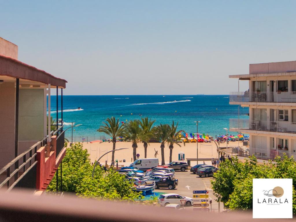 een uitzicht op een strand met een parkeerplaats en de oceaan bij Larala 03 - Nuevo apartamento frente al mar en el Arenal en Jávea in Jávea