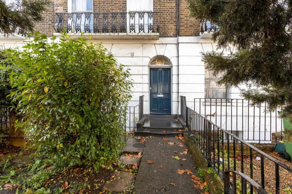 a house with a blue door and a fence at Camden Apartment By Morethanstays in London