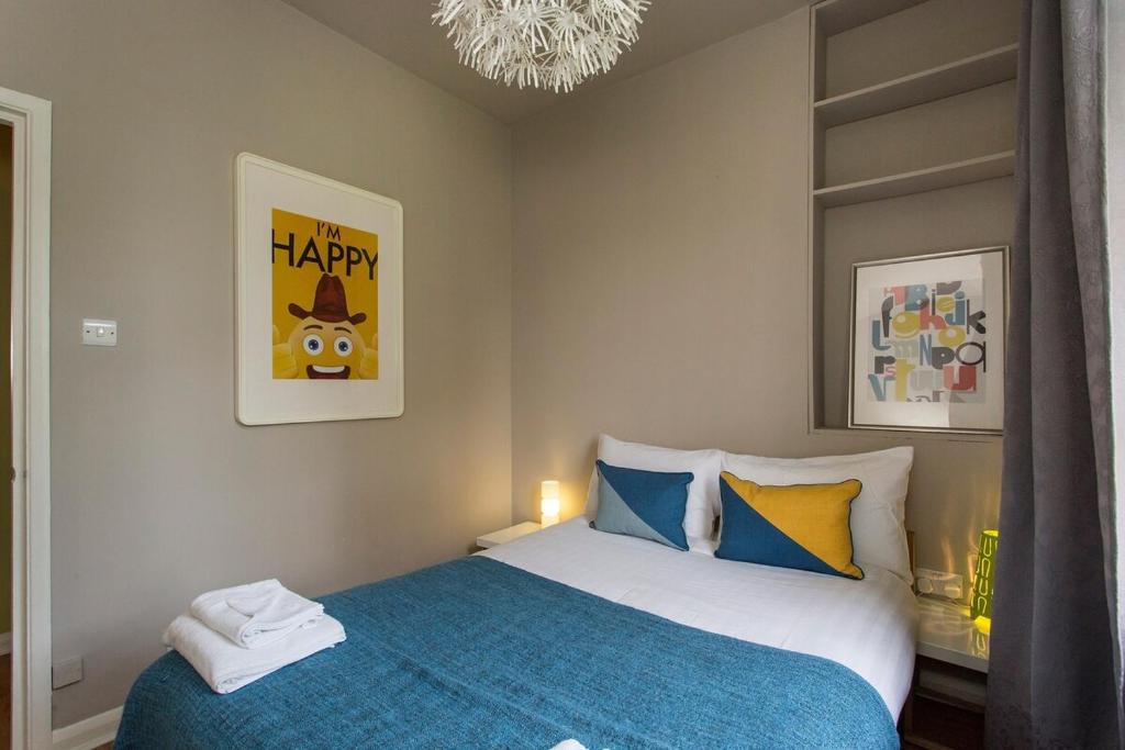 a bedroom with a bed with a blue blanket at Camden Apartment By Morethanstays in London