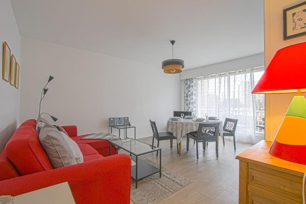 uma sala de estar com um sofá vermelho e uma mesa em Appt agréable avec balcon au sud-ouest de Caen em Caen