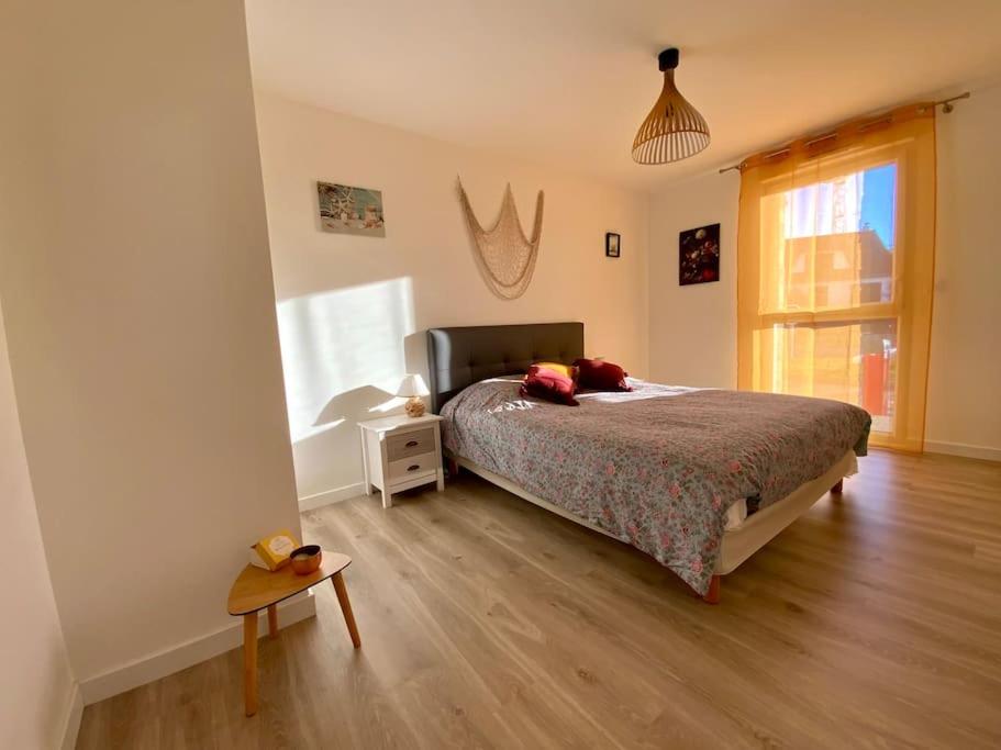 een slaapkamer met een bed en een houten vloer bij L'appel du large in Arzon