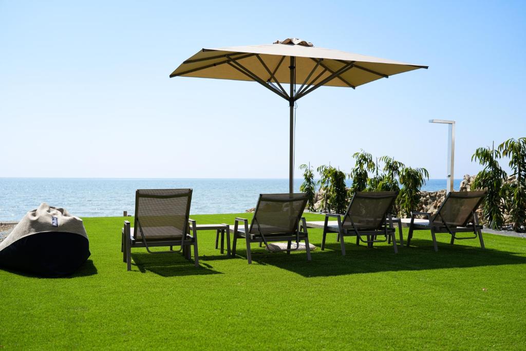 - un groupe de chaises et une table avec un parasol dans l'établissement Meneou Houses by the Sea, à Larnaka
