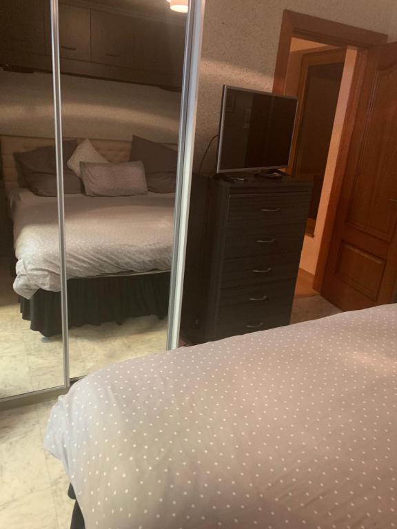 Schlafzimmer mit einem Bett, einem TV und einem Spiegel in der Unterkunft Ruthven in Stevenston