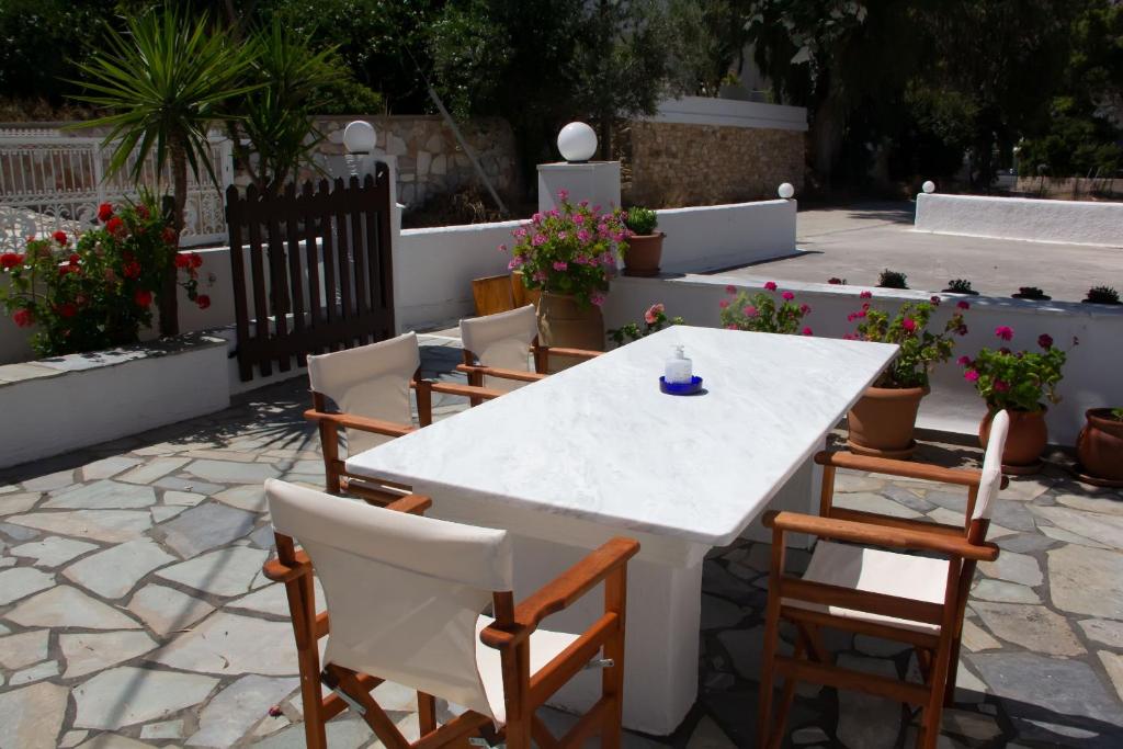 加利薩斯的住宿－阿里斯提迪公寓，鲜花庭院里的白色桌子和椅子