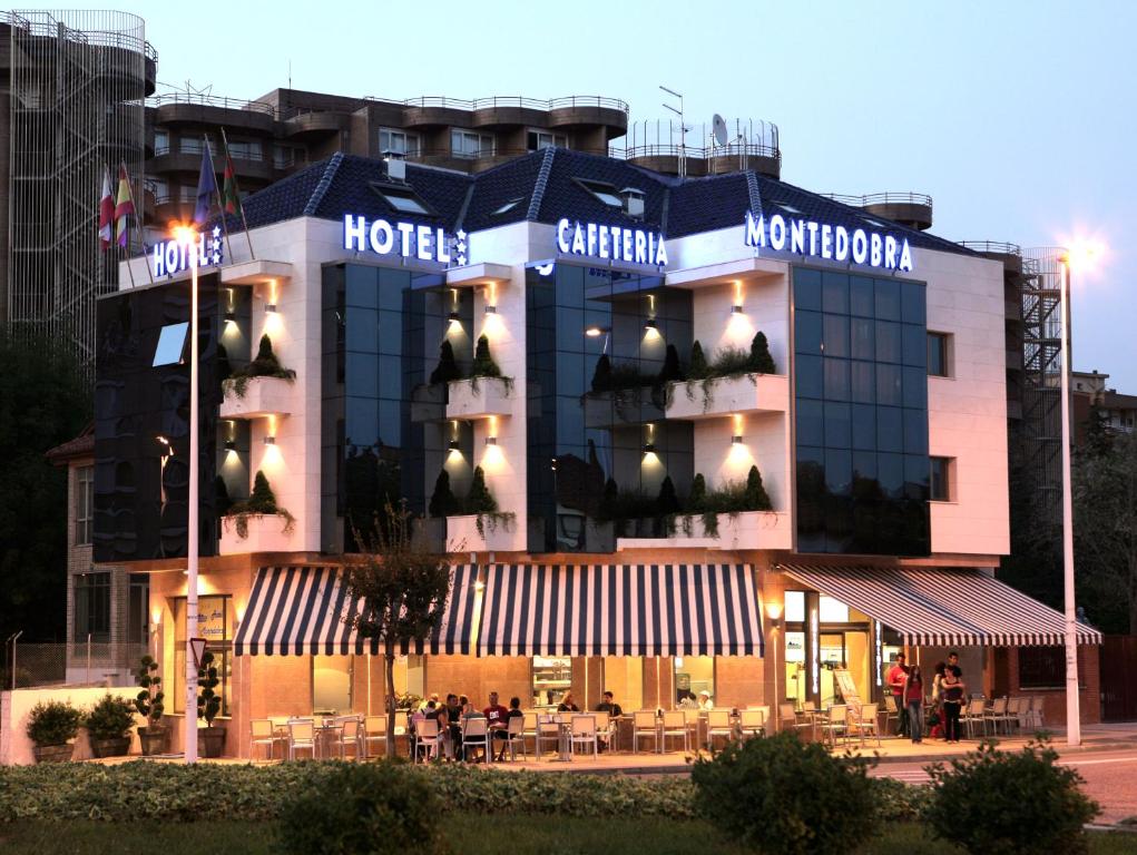 a hotel building with a restaurant in front of it at Hotel Montedobra in Torrelavega