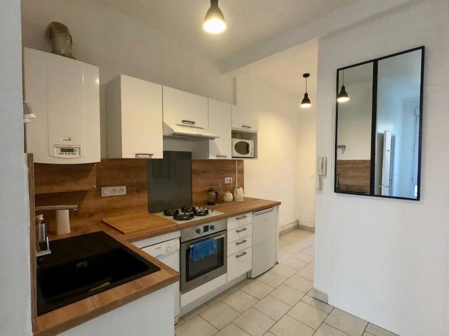 uma cozinha com armários brancos e um forno com placa de fogão em Rochereau de la Clautre em Périgueux