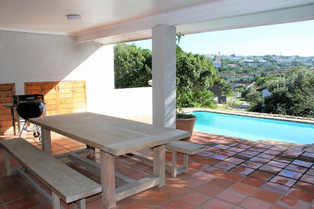 un tavolo e una panca su un patio con piscina di 36 @ Plett! a Plettenberg Bay