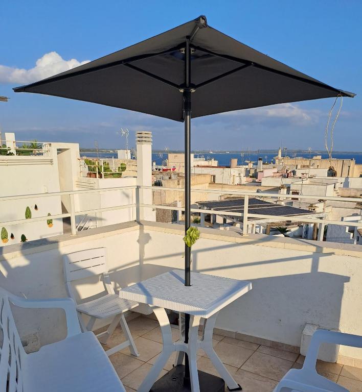 a table and chairs with an umbrella on a roof at Cinque terrazze - Casa d'epoca con vista mare in Gallipoli
