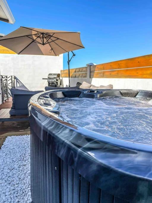 a hot tub with an umbrella on a patio at Villa cap zen and spa in Petite Île
