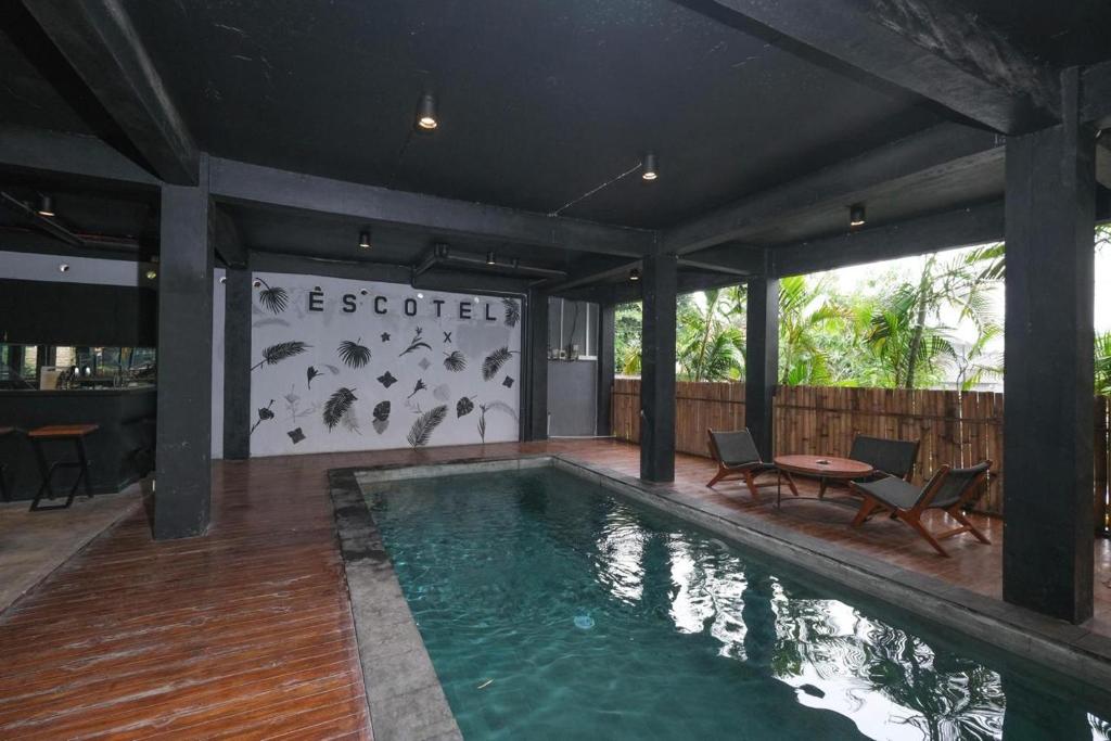 een zwembad in een huis met een tafel en stoelen bij Escotel Krisnantara in Canggu