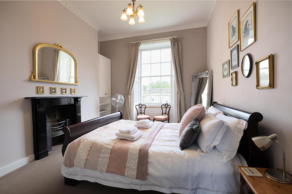a bedroom with a bed with a fireplace and a mirror at Crescent Green in Bath