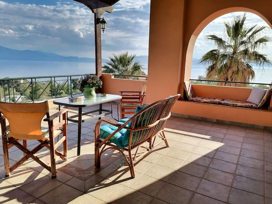 a patio with a table and chairs and a view of the ocean at Coastal SeaCharm - Theotokos Sandyfill Getaway in Nerotriviá