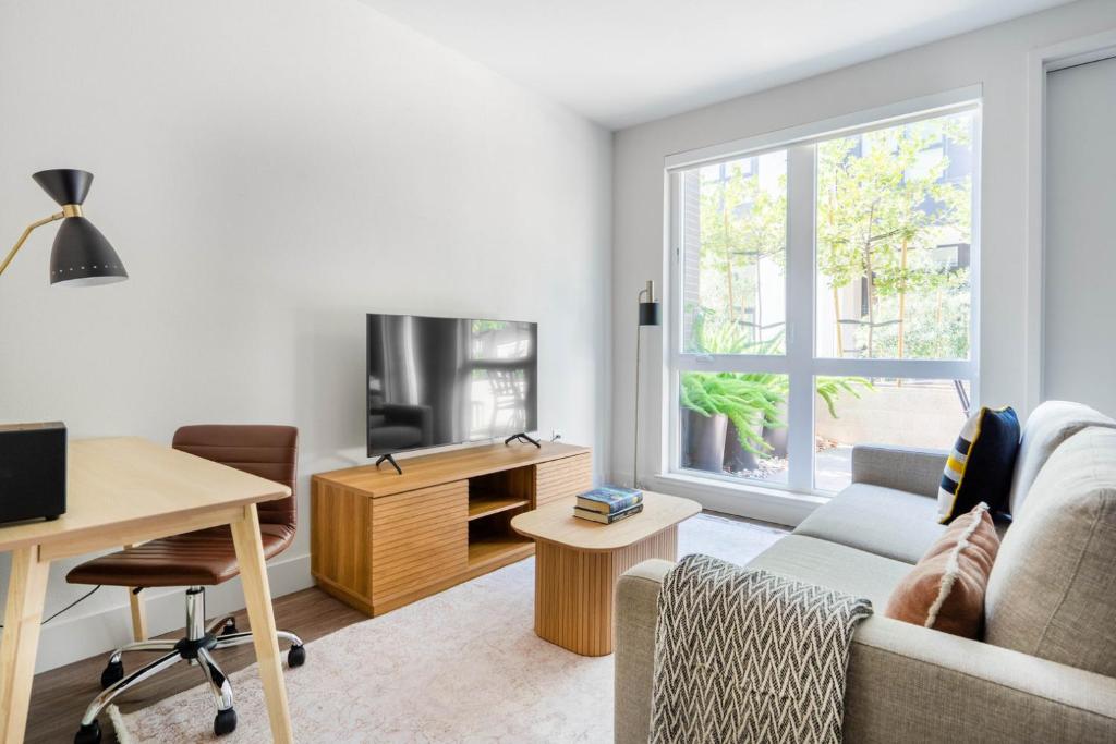 a living room with a couch and a desk and a tv at Mountain View Studio w Gym WD nr 101 SFO-673 in Los Altos