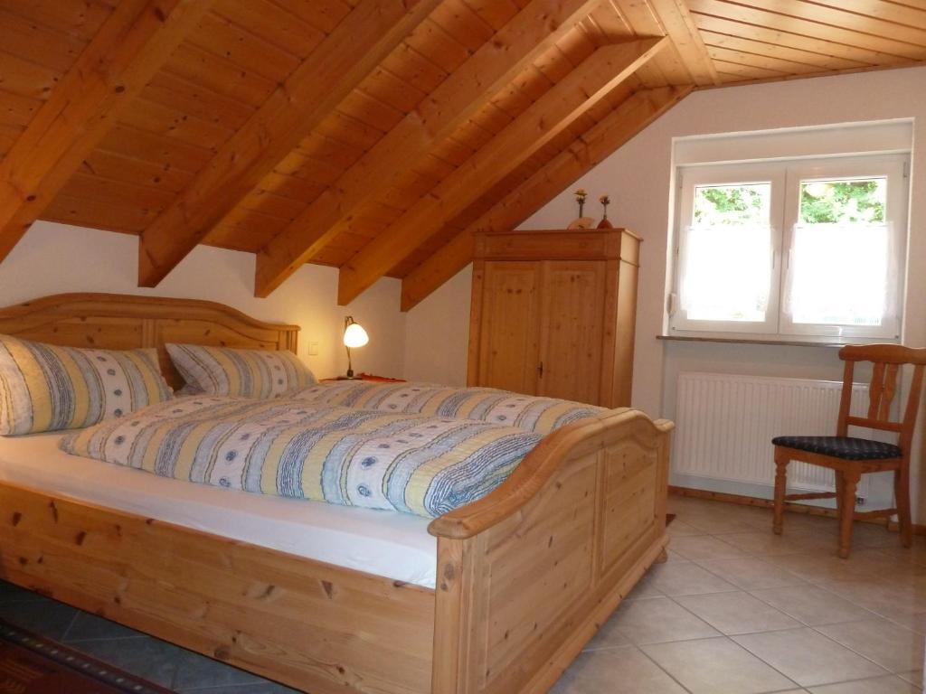 a bedroom with a wooden bed and two windows at Gästehaus Hoffmann in Dörrenbach