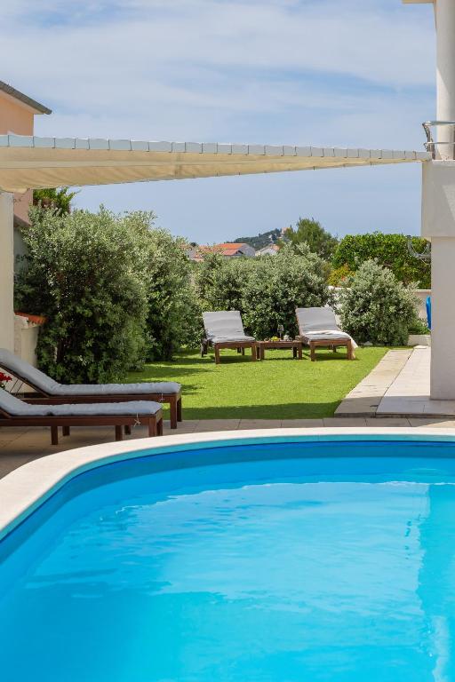 a swimming pool in a yard with two benches at Apartments Tihi III in Vodice