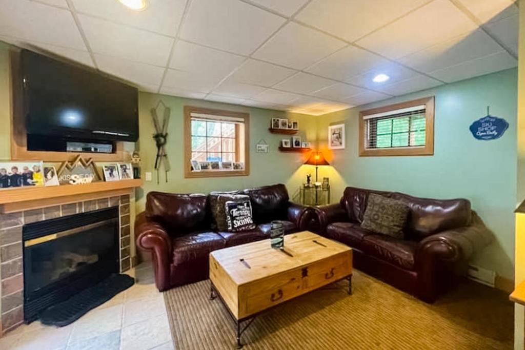 uma sala de estar com mobiliário de couro e uma lareira em Boyne Mountain Getaway, Unit B em Boyne Falls