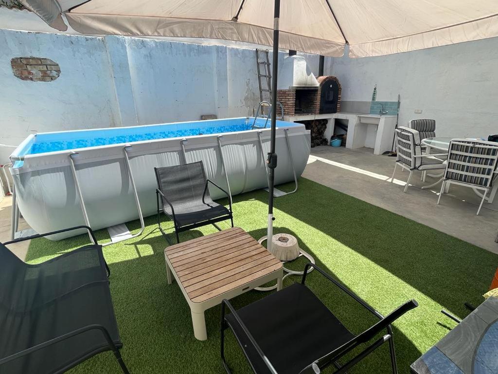 a patio with a tub and chairs and a table and an umbrella at Cuencaloft El Patio de Enrique in Cuenca