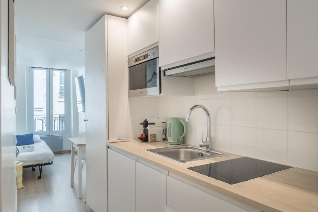 - une cuisine blanche avec évier et comptoir dans l'établissement Lavie Maison Paris AC Retreat, à Paris