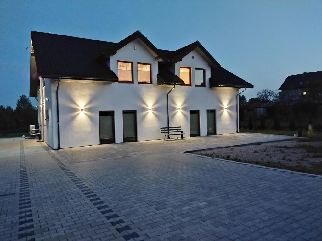 Una casa blanca con luces en el costado. en Villa na Chabrowej, en Miedziana Góra
