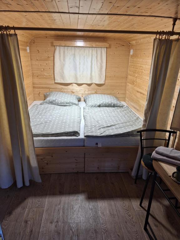 a bed in a wooden room with a window at Maringotka Lesní Mlýn in Nový Rychnov