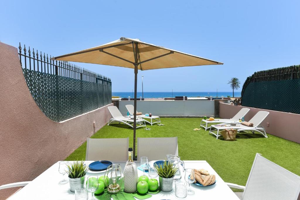 a table with an umbrella and some chairs and grass at Chalet Santa Ana 24 by VillaGranCanaria in Playa del Ingles