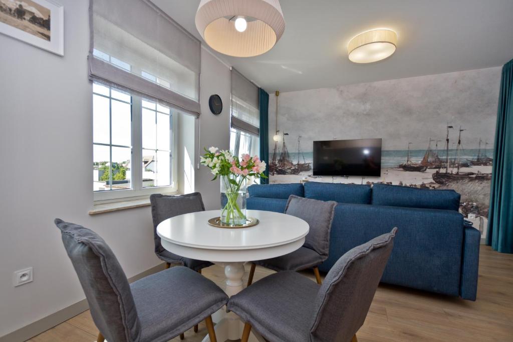 sala de estar con mesa y sofá azul en Apartament Wejhera, en Puck