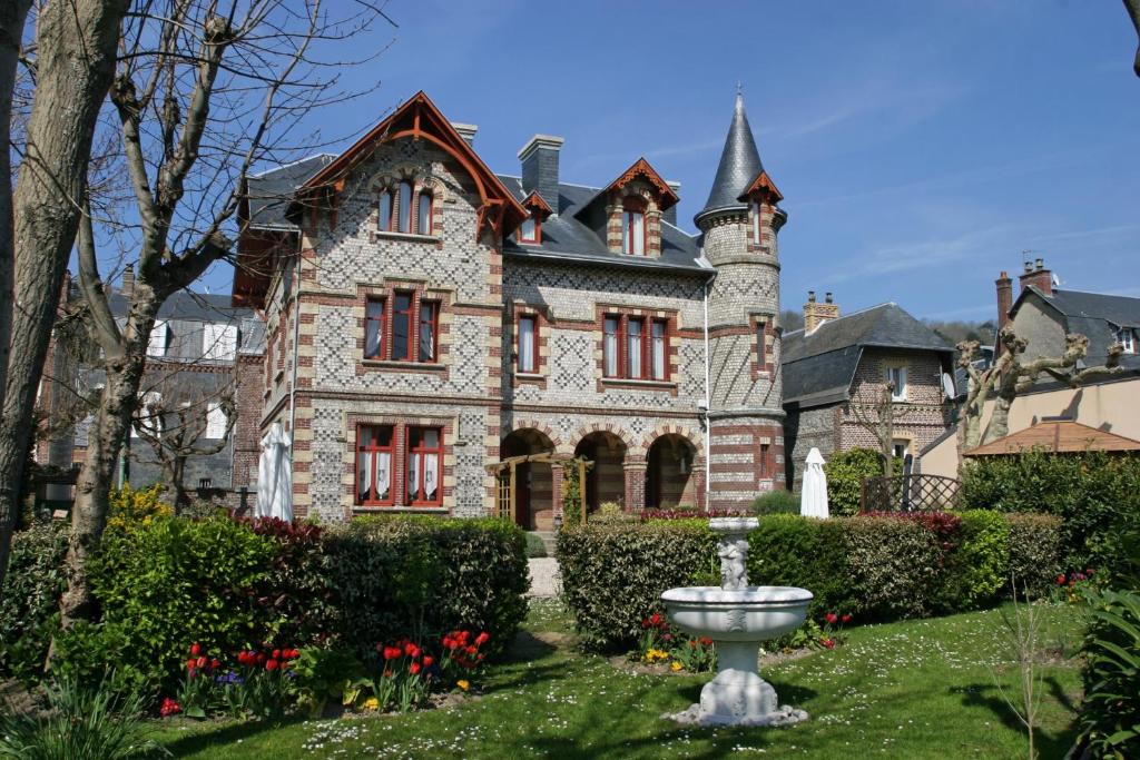 een oud huis met een fontein ervoor bij La Villa Bligny in Étretat