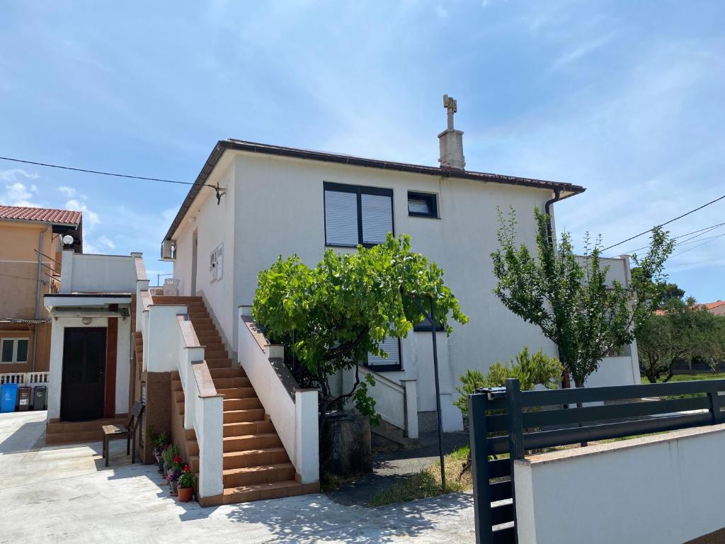 a white house with stairs in front of it at Guesthouse Šimag in Rab