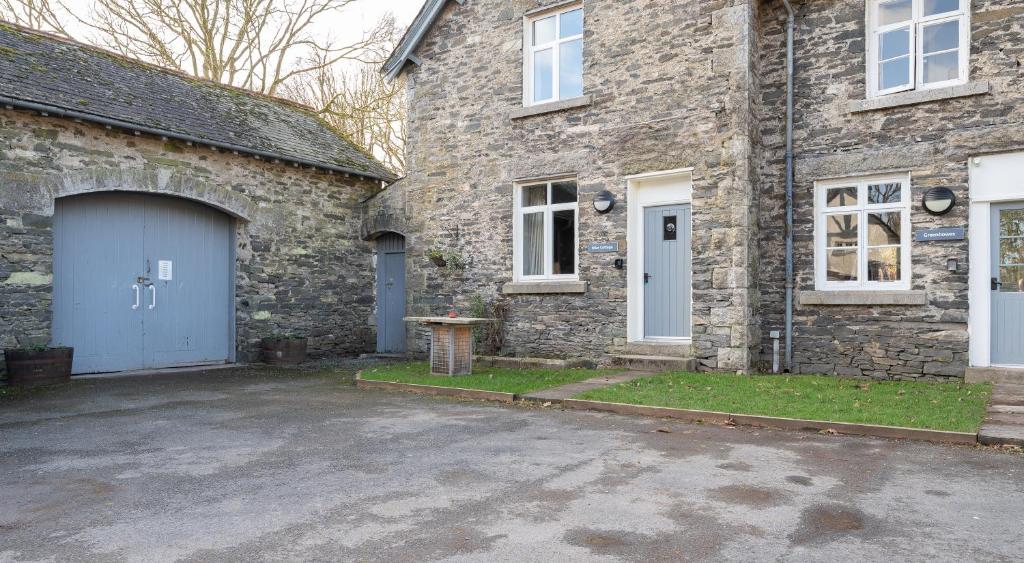 a brick house with a garage and a driveway at Briar Cottage in Rusland