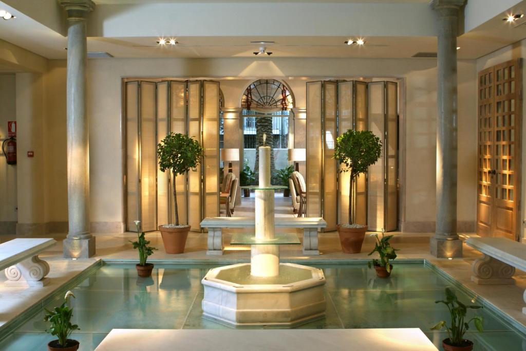 a lobby with a fountain in the middle of a building at Villa Oniria in Granada