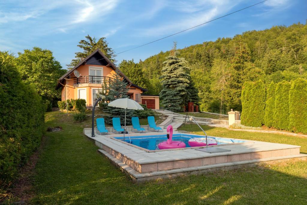a pool with chairs and an umbrella in front of a house at Villa Tratea - With Pool in Tomić Draga