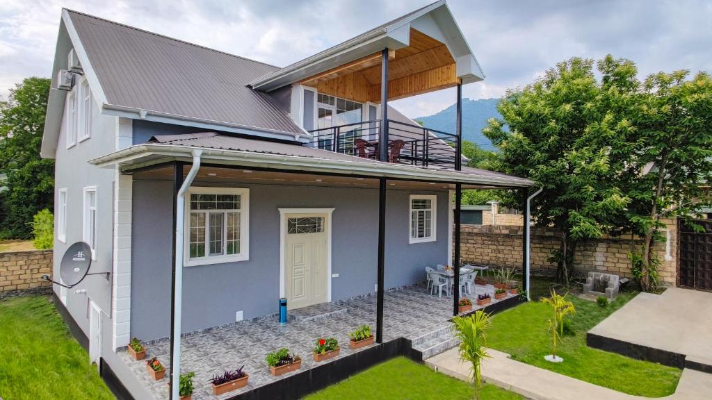 een huis met een dakuitbreiding en een veranda bij Qafqaz Flower Villa in Gabala