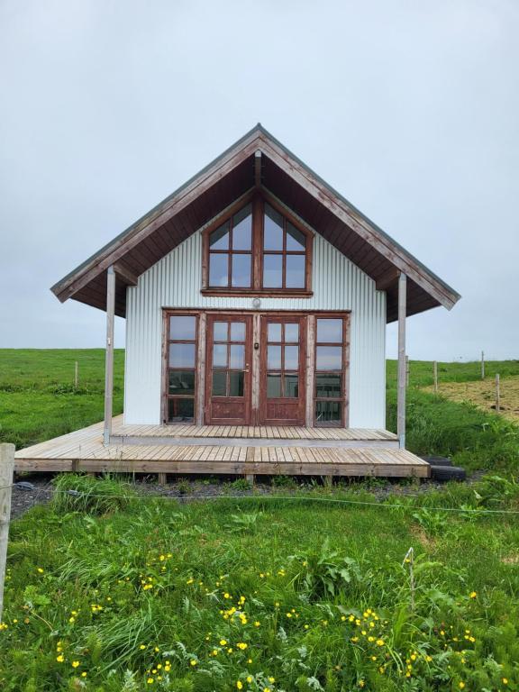 una pequeña casa en un campo con terraza de madera en Hólar countryside cabin 1 en Selfoss