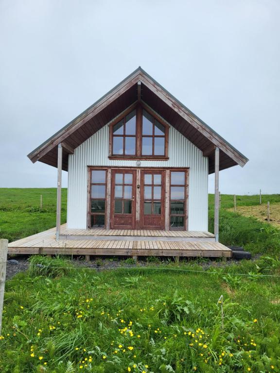 Una pequeña casa en un campo con una terraza de madera. en Hólar countryside cabin 1, en Selfoss