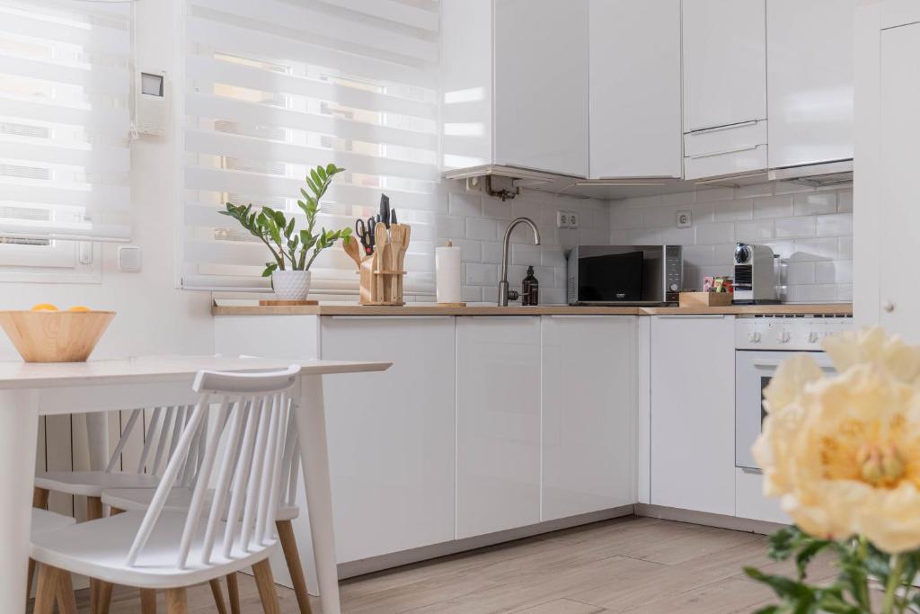 cocina con armarios blancos, mesa y sillas en Amazing apartment in Huertas, en Madrid