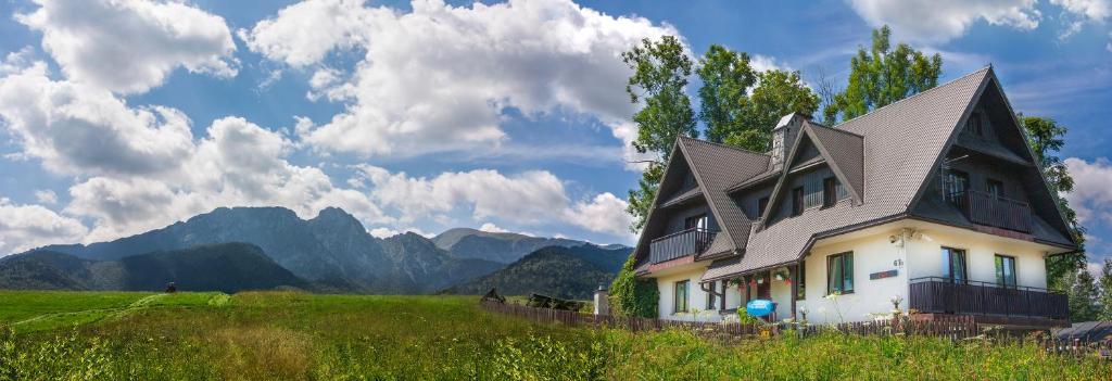 a house in a field with mountains in the background at Willa Na Wierchu in Zakopane