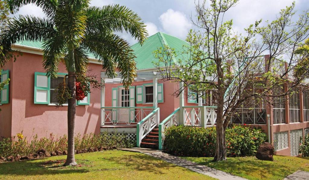 a pink house with a palm tree in front of it at Mandevilla Nevis in Cliftons