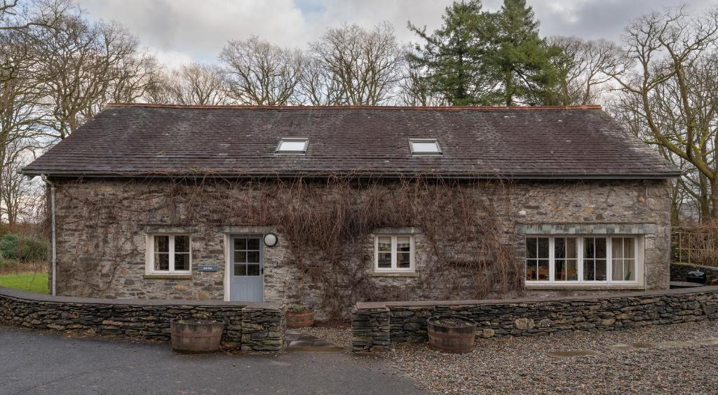 a stone house with a roof and two windows at Bull Pen in Rusland