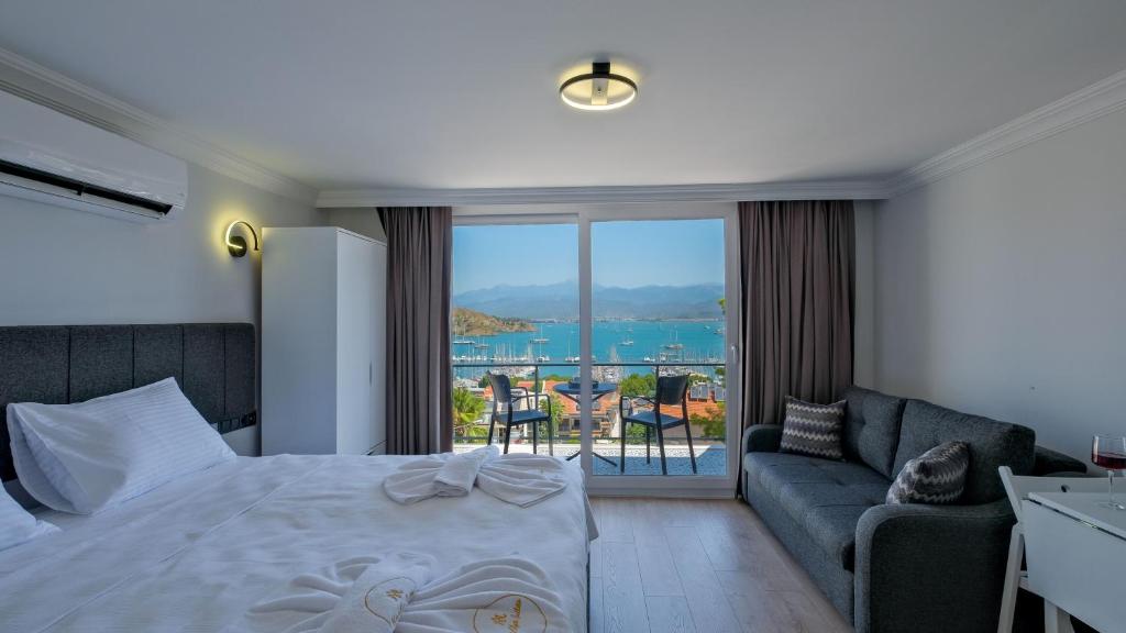 a bedroom with a bed and a couch and a balcony at Miralya Suites in Fethiye