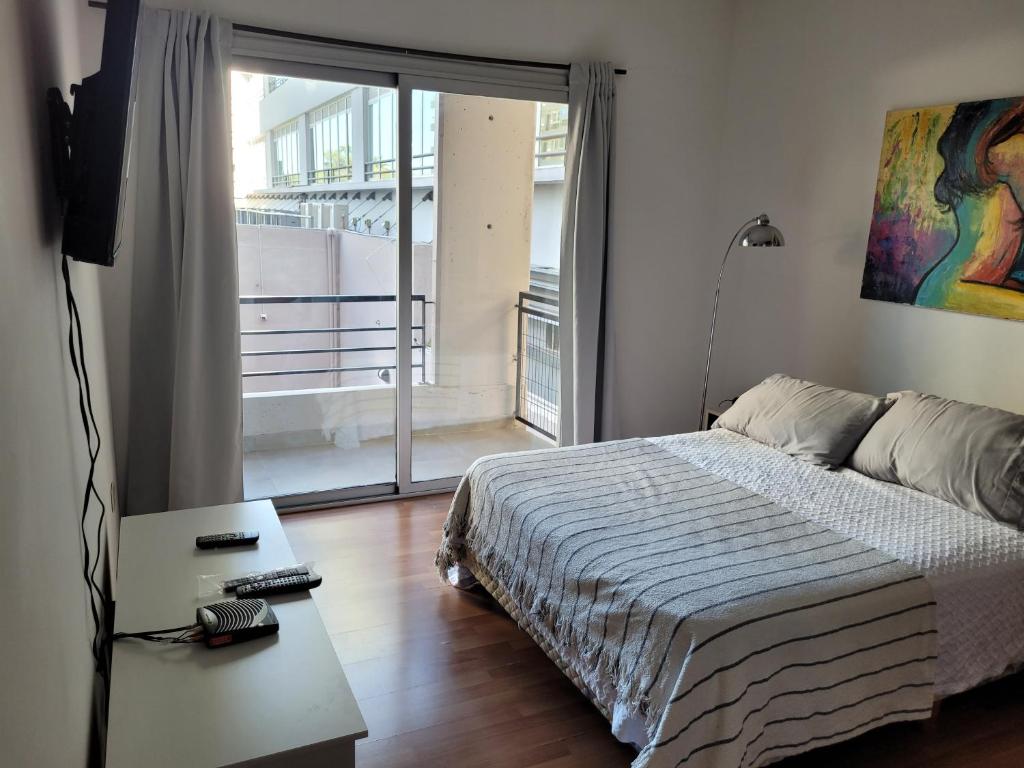 1 dormitorio con cama y vistas a un balcón en Olivos Suites in 