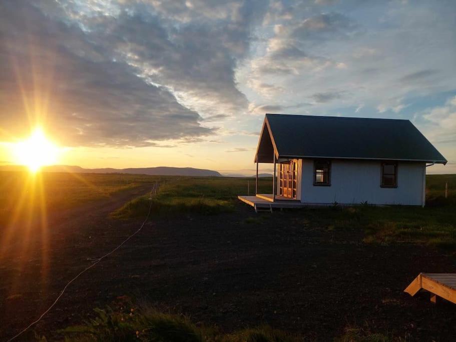 a small house in a field with the sun setting at Hólar Countryside Cabin 2 in Selfoss